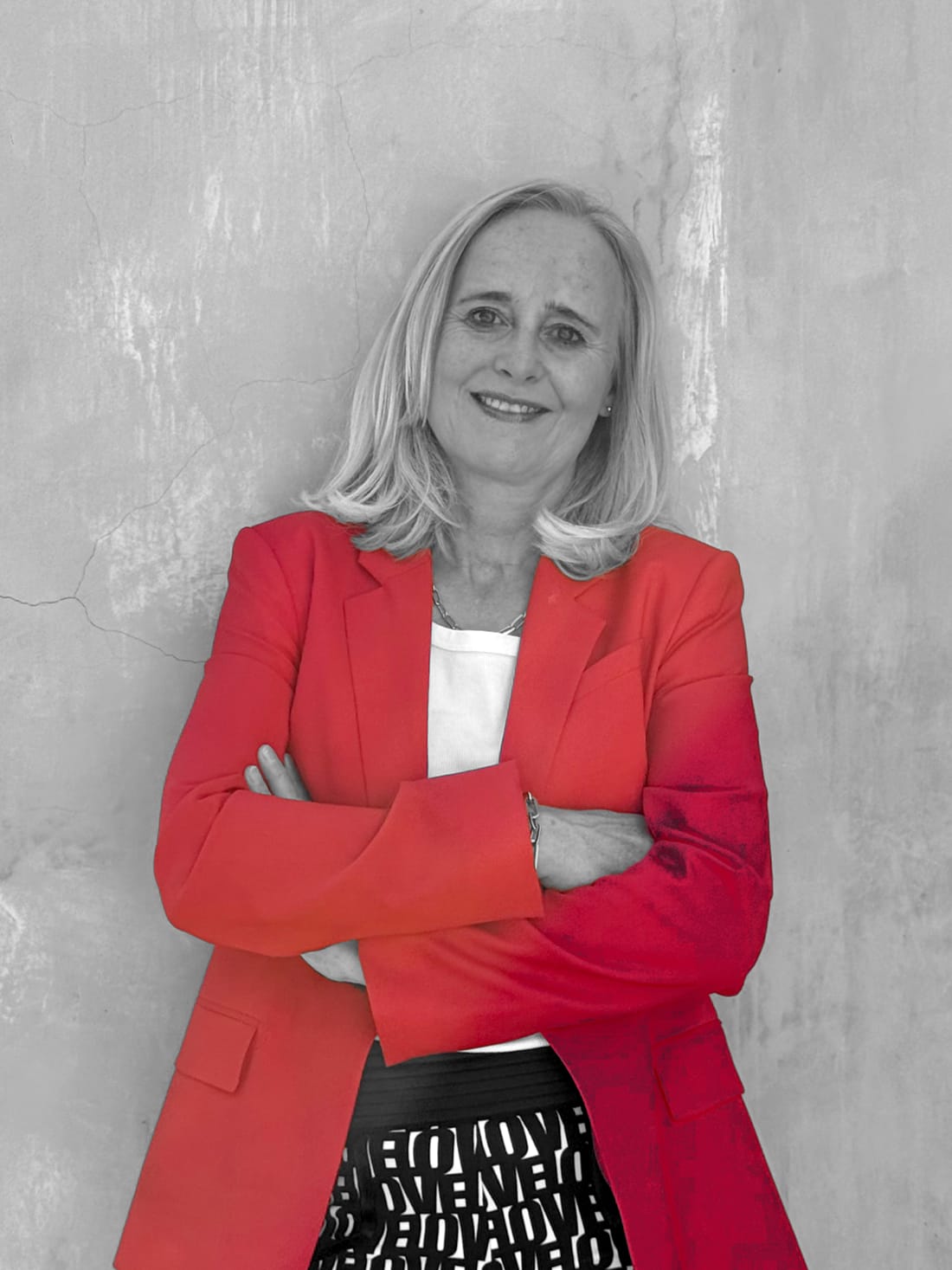 Maike Buhr in a red blazer, arms folded, in front of a concrete wall